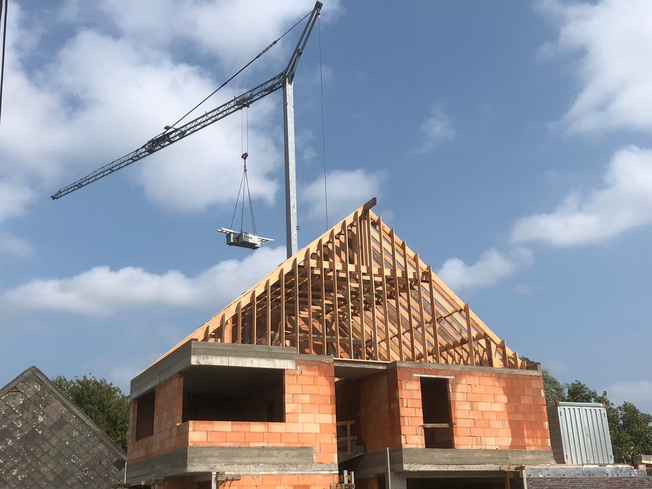 Torenkraan die een last boven het houten gebinte van een nieuwbouwwoning hangt