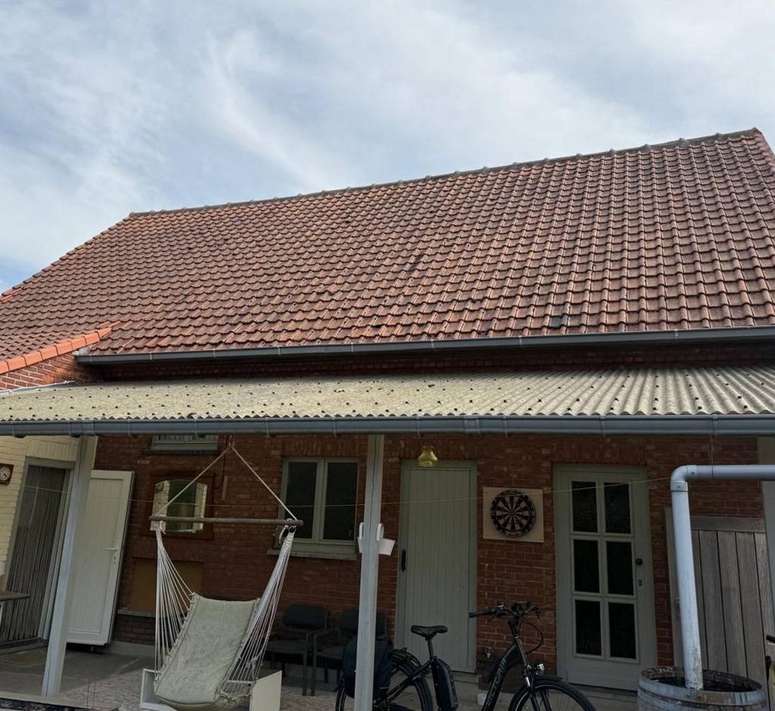 Verweerd pannendak boven een terras, met daaronder een afdak in golfplaten