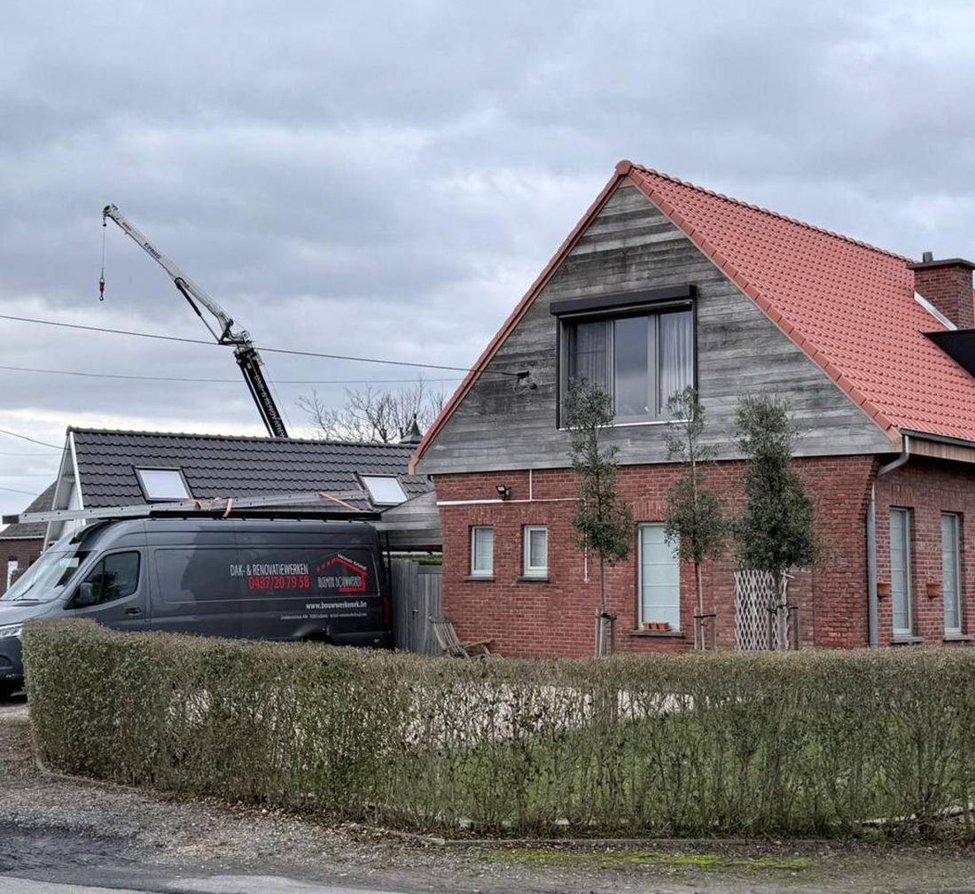 Woning met een nieuw rood pannendak, met de bestelwagen en de kraan van Bouwwerken VK ernaast