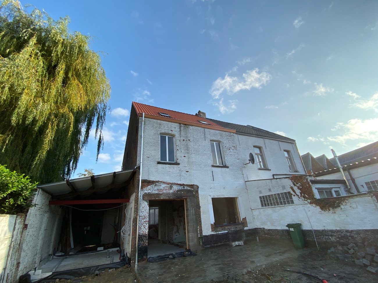 Oude witgekalkte woning in volle renovatie, met een nieuw pannendak met dakvensters en een luifel